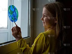 可爱的小女孩在家里的窗户上画着4K的星球。4月22日地球日快乐。创造性的家庭休闲