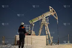石油工人检查油泵。石油钻机，现场抽油泵千斤顶与暴风雪和工人。化石能源的概念。