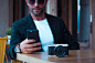 man camera mobile phone technology pose sunglasses table bar watch wait dslr photography photographer device telephone 
