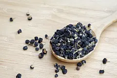 黑枸杞或黑枸杞，放在桌上的木勺里。中药中常用的草药。卫生保健的概念。
