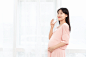 摄图网_501369104_一个孕妇站着在客厅喝水（非企业商用）