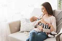 坐在沙发上哄新生儿的漂亮妈妈