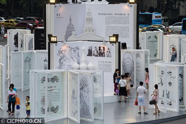 ↑6月11日，人们在“立体书”雕塑里参观...