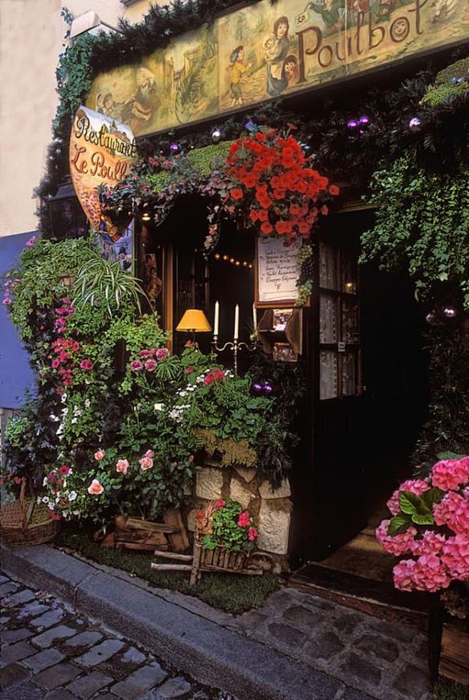 这是位于巴黎的一所餐厅，店门被鲜花绿植餐...