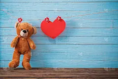 旧木制背景上有红心的泰迪熊。情人节
