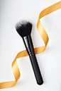 High Angle View Of Make-Up Brush And Ribbon Over White Background