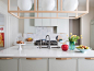 Kitchen with White Counters and Cabinets any White Circular Hanging Lamps.
