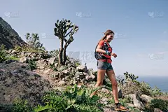 女子在加那利岛的一条山路上跑过乡村。海洋的观点