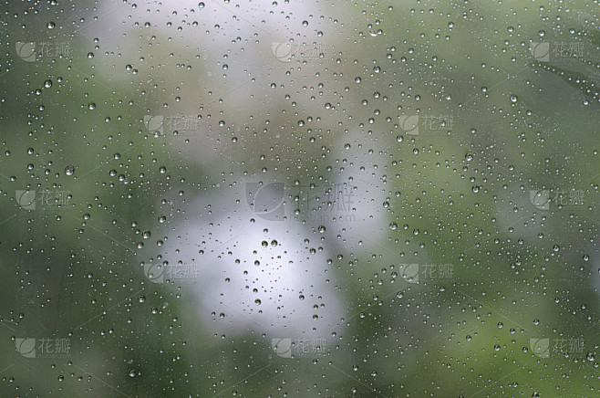 玻璃上的雨滴和绿树背景的散景
