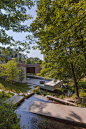 This may contain: the house is surrounded by trees and water, with an open area to sit on