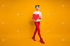 全身照片相当有趣的女士拿纸心走街创意约会邀请男友穿心形毛衣红裤子鞋孤立黄色背景