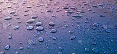 美丽的水滴背景。雨滴落在蓝色金属表面。