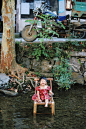 girl sitting on chair surrounded by body of water