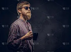 一个时髦的家伙戴着太阳镜，穿着一件老式衬衫，在黑色的背景上举着一杯咖啡的特写。
