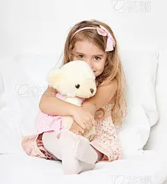 Adorable little child girl sit in bed with teddy bear