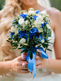 手持白玫瑰和蓝色花朵的婚礼花束