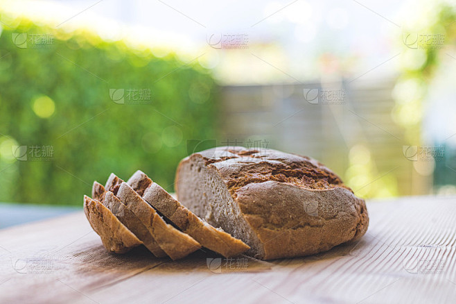 Fresh rustic bread in slices on wooden cutting boa