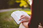 Woman sits in the park reading Colossians in the bible