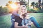 woman holding baby sitting on green grass field under sunset