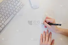 一个女人的手签名明信片在办公室的特写，从上往下看