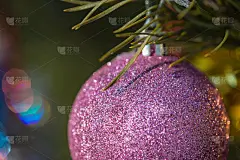 紫色的小玩意儿挂在装饰好的圣诞树上。圣诞节的背景