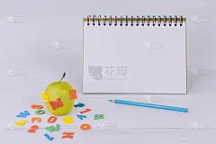 回到学校的模型。绿苹果，彩色字母和记事本背景。