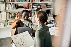 在办公室从事新业务项目时，快乐有创造力的同事们相互击掌致意。