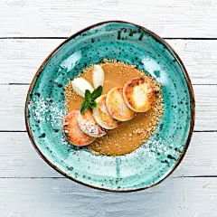 奶酪煎饼配焦糖，冰淇淋和坚果。早餐。在盘子里。前视图。平面排版自由复制空间。