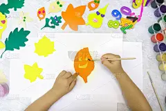 秋天的工艺品。孩子用纸和橡皮泥制作五颜六色的有趣的叶子。回到学校。
