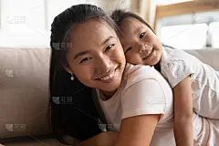 有吸引力的年轻亚洲母亲抱背可爱的小孩子。