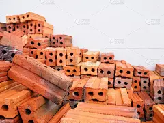 许多红色粘土砖排在白墙旁边，等待用作建筑基础，耐用，坚固，极其难磨损。最常用的抹灰是在墙面的内层涂上