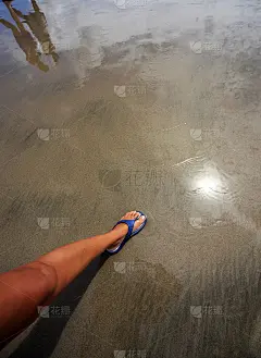被晒伤的女性腿在潮湿的沙子上