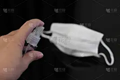有人在白色口罩上喷洒酒精消毒