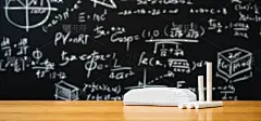 教育背景的概念。板擦和粉笔放在木桌上，黑板上有许多数学公式。