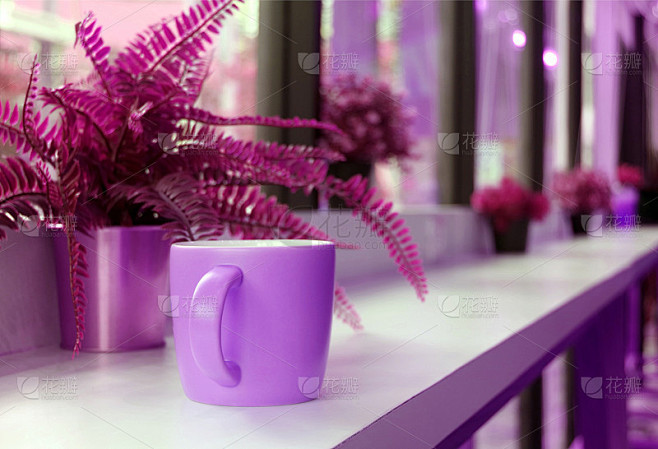 咖啡杯放在咖啡厅的长桌上，上面有紫色和洋...