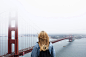 A blonde woman with a backpack looking at the Golden Gate Bridge