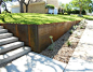 Modern metal retaining wall with planted stone bioswale.