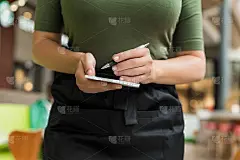 裁剪的女服务员在咖啡馆或餐厅用记事本和笔准备点菜的图像。