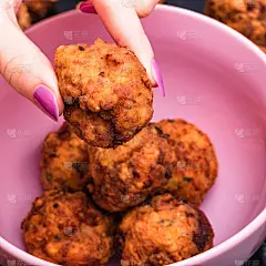 粉红色的碗，配上香料炸肉丸。自制的食物。手里拿着一个炸肉丸子。