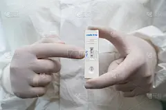 严密抗原COVID-19快速检测。快速快速诊断试验阳性。医生穿着防护服和手套拿着抗原测试