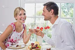 幸福的年轻夫妇举杯共饮美食