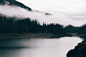 calm body of water surrounded by mountain and fogs