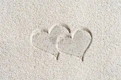沙滩上两颗绘有情人的心。概念