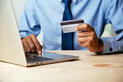 手持信用卡使用笔记本电脑的男子。网上购物的概念。