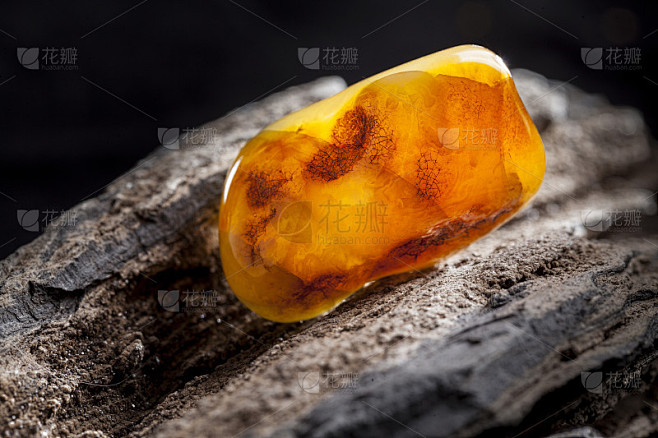 天然琥珀。一块不透明的黄色天然琥珀，镶嵌在大块深色的石头上。