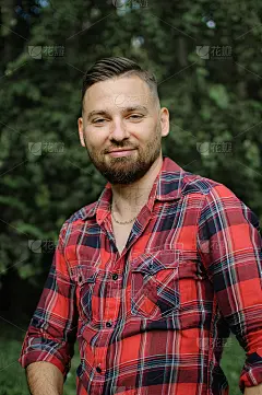 户外肖像轻松英俊的年轻人与胡子在公园的绿树背景。潮人风格的概念。