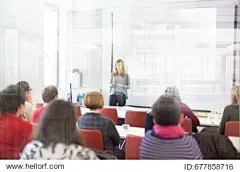Speaker giving presentation in lecture hall at university. Participants listening to lecture and making notes.