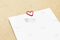 牛皮纸背景上的空白白纸。心形的红色回形针