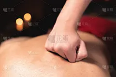 特写:年轻的白人男性按摩在一间暗室康复按摩室里，它为一个运动员和一个病人提供专业的按摩