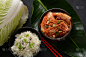 黑色碗里的泡菜和米饭，还有筷子。韩国食物